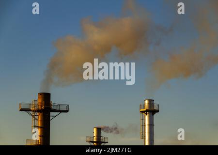 Goiania, Goiás, Brasile – 04 agosto 2022: Fumo proveniente da tre camini di una fabbrica. Inquinamento atmosferico da fumo che esce dal camino. Foto Stock