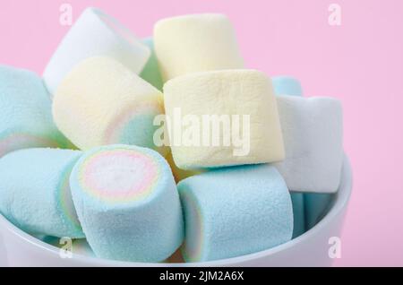 Mini marshmallow colorati in tazza su sfondo rosa. Foto Stock