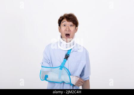 Ritratto di uomo asiatico con braccio rotto e collo sensazione di sorpresa e scioccato isolato su sfondo bianco copia spazio Foto Stock