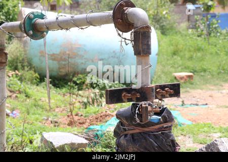 Pompa dell'acqua sommergibile collegata a tubi metallici e supporti arrugginiti alla luce del giorno Foto Stock