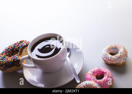 Vista angolare del caffè nero fresco con spazio copia e ciambelle su sfondo bianco Foto Stock
