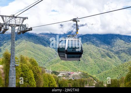 Ascensore aereo sullo sfondo di una foresta verde e montagne innevate Foto Stock