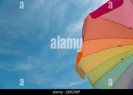 Guardando verso l'alto vista di colorati ombrelloni da spiaggia e cielo blu brillante. Foto Stock