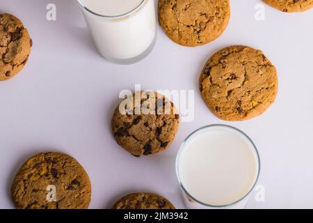 Vista dall'alto del latte in bicchieri con biscotti su sfondo bianco, spazio copia Foto Stock