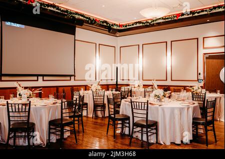 Un interno di un ristorante vuoto con tavoli bianchi e sedie nere su prenotazione Foto Stock