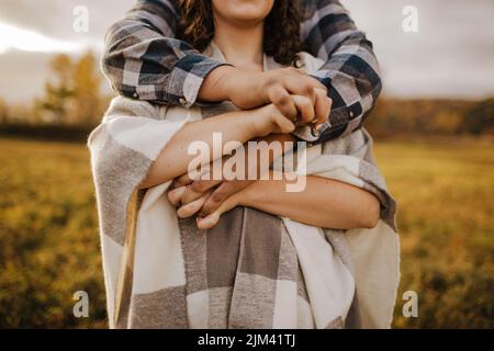 Un primo piano di una coppia che abbraccia l'esterno alla luce del giorno con sfondo sfocato Foto Stock