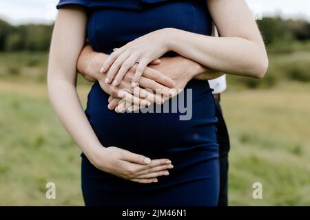 Un colpo di primo piano dei futuri genitori che abbraccia una pancia incinta di 38 settimane Foto Stock