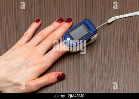 Pulsossimetro su dito indice femmina per la misurazione del polso e della saturazione di ossigeno all'interno dei globuli rossi Foto Stock