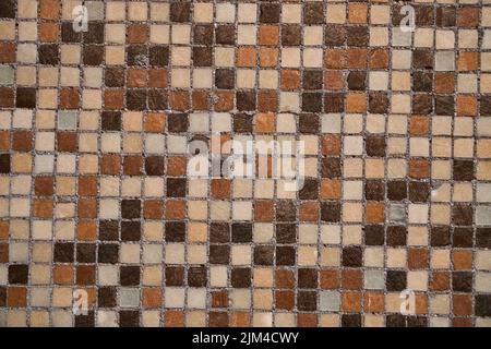 Piccole piastrelle quadrate in ceramica in diverse sfumature di marrone con fondo marrone grouting Foto Stock