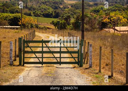 Goiania, Goiás, Brasile – 24 luglio 2022: Un cancello di legno dipinto di verde all'ingresso di una fattoria sul lato di una strada a Goias. Foto Stock