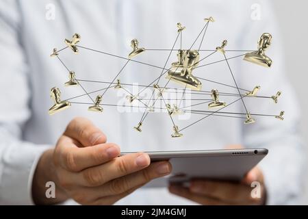 Un primo piano delle icone illustrate delle persone connesse vicino alle mani che tengono un tablet Foto Stock