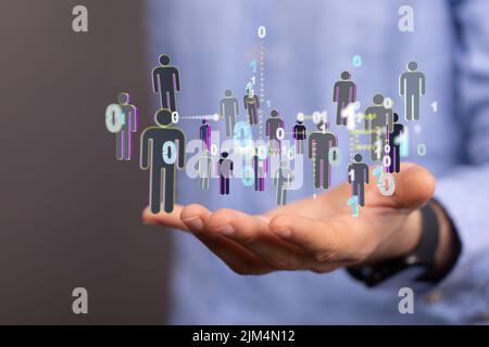 Primo piano di un rendering 3D di figure umane digitali con codici binari che galleggiano sulla mano di un uomo Foto Stock