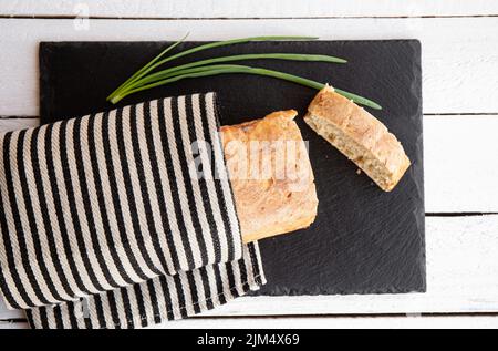 Appartamento Lay vista appena sfornato farina di grano pane di farina di casa su tavola di servizio in pietra nera in cucina casa. Foto Stock