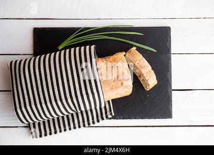 Appartamento Lay vista appena sfornato farina di grano pane di farina di casa su tavola di servizio in pietra nera in cucina casa. Foto Stock