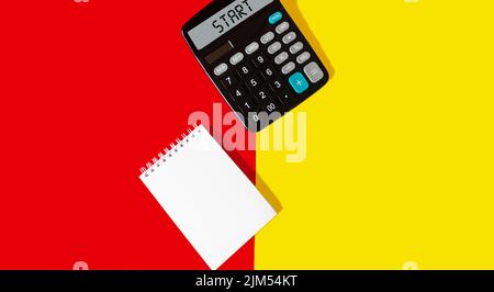 Testo iniziale sul display della calcolatrice con blocco note su sfondo giallo rosso Foto Stock