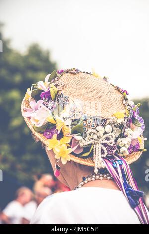 Una foto verticale di una tradizionale ballerina inglese Maypole con un cappello floreale con nastri colorati Foto Stock