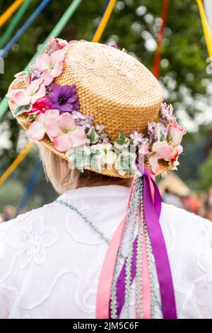 Una foto verticale di una tradizionale ballerina inglese Maypole con un cappello floreale con nastri colorati Foto Stock
