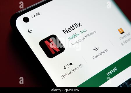 Applicazione NETFLIX visualizzata in Google Play Store sullo schermo dello smartphone su sfondo rosso. Foto ravvicinata con messa a fuoco selettiva. Stafford, Regno Unito Foto Stock