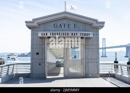 Un terminal dei traghetti della Baia di San Francisco con un traghetto e il Ponte della Baia di San Francisco sullo sfondo. Foto Stock