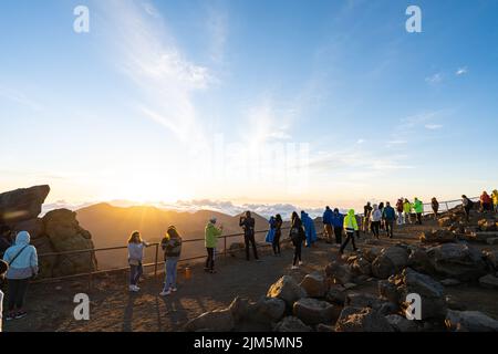 I turisti si sono riuniti in un punto panoramico sulla cima del Cratere di Haleakala per osservare l'alba. Foto Stock