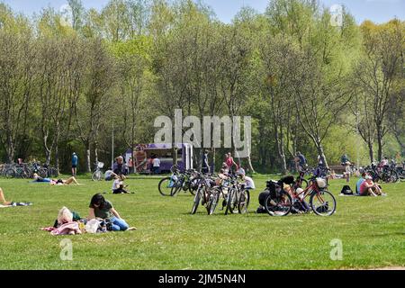 La gente che riposa sull'erba verde vicino al lago Rusalka in una giornata di primavera soleggiata Foto Stock