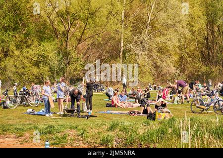 La gente che riposa sull'erba verde vicino al lago Rusalka in una giornata di primavera soleggiata Foto Stock