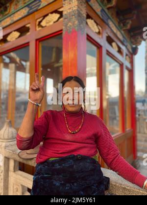 Una donna asiatica di fronte ad un edificio tradizionale nella città di Lhasa in Tibet, Cina Foto Stock