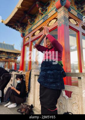 Una donna asiatica di fronte ad un edificio tradizionale nella città di Lhasa in Tibet, Cina Foto Stock