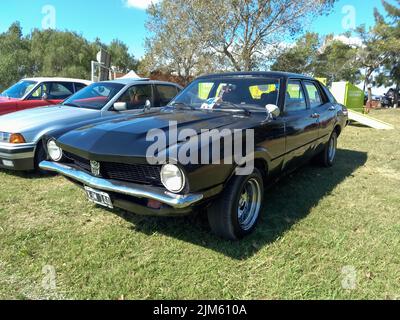 Vecchia nera Ford Maverick quattro porte berlina 1971 - 1977 parcheggiata in campagna. Natura, erba, alberi. Giorno di sole. Spettacolo di auto classica. CopySpace Foto Stock