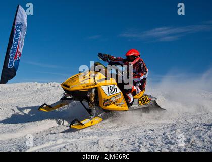 Motoslitta in competizione negli sport estremi. Su una motoslitta, uno sportivo. È una giornata di sole per una gara invernale Foto Stock