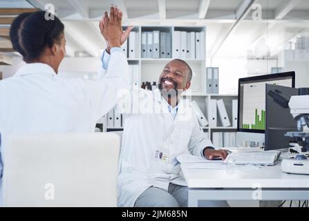 Grido, grido, gridiamo tutti per la scienza: Due scienziati che si danno a vicenda un massimo di cinque mentre conducevano la ricerca in un laboratorio. Foto Stock