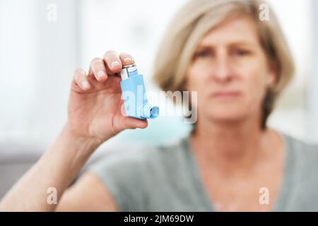 Un salvavita che si adatta alla mia tasca. Un anziano che tiene un inalatore per l'asma a casa. Foto Stock