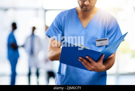 Medico, medico e lavoratore che legge da un file, cartella o forma mentre lavora in un ospedale moderno. Analisi infermiere, chirurgo o gp Foto Stock