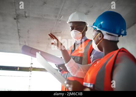 Costruzione che non compromesso sulla qualità. Un giovane uomo e una donna che vanno oltre i piani di costruzione in un cantiere. Foto Stock