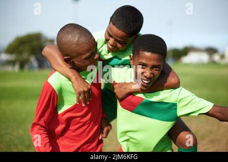 Il loro spirito di squadra corre sempre alto. Un gruppo di ragazzi che gioca a calcio in un campo sportivo. Foto Stock