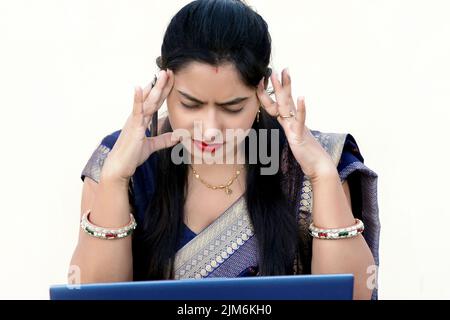 Una donna indiana che lavora su un notebook con mal di testa Foto Stock