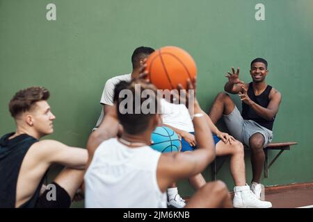 Qui, catch. Un gruppo di giovani sportivi appesi su un campo da basket. Foto Stock