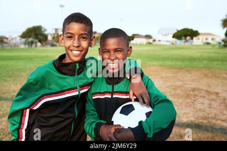 Erano i migliori amici e compagni di squadra. Ritratto di due ragazzi che giocano a calcio su un campo sportivo. Foto Stock