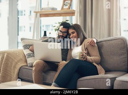 Niente rende la vita più comoda della rete. Una giovane coppia che usa un computer portatile sul divano di casa. Foto Stock