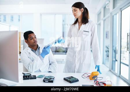 Il migliore nel settore della riparazione di computer. Un giovane uomo e una donna che ripara l'hardware di computer in un laboratorio. Foto Stock