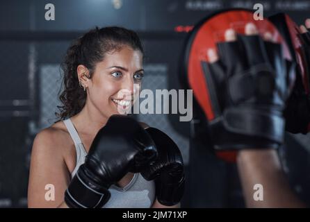 Un ottimo modo per migliorare la resistenza. Una giovane donna che pratica con il suo allenatore in una palestra di boxe. Foto Stock
