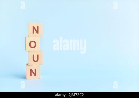 Concetto di sostantivo o sostantivo nell'educazione grammaticale inglese. Blocco di legno Crossword puzzle piatto adagiare su sfondo blu. Foto Stock