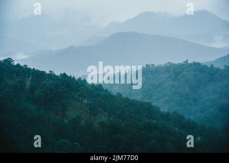 Una bella vista di un paesaggio con colline e montagne coperte di nebbia Foto Stock