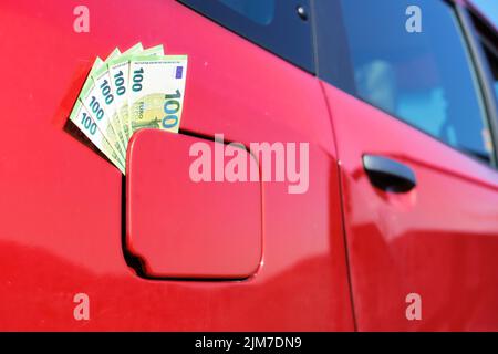 Un pacchetto di cento banconote in euro nel tappo del serbatoio del carburante di un'automobile. Simbolo per l'aumento del prezzo del carburante. Foto Stock