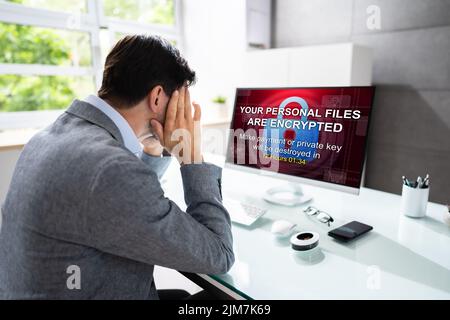 Preoccupato per il businessman guardare il computer con Ransomware Word sullo schermo sul posto di lavoro Foto Stock