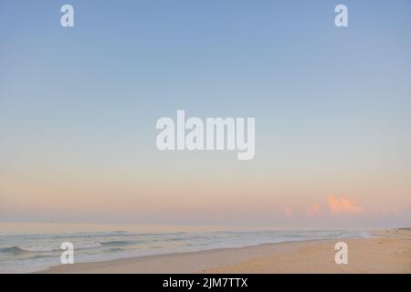 Una vista panoramica di una spiaggia di sabbia contro il mare al tramonto a Fort Morgan, Alabama Foto Stock