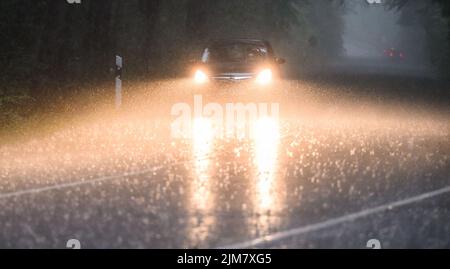 Sehnde, Germania. 05th ago 2022. Un'auto percorre una strada di campagna nella regione di Hannover durante una tempesta di tuoni con forti piogge. Credit: Julian Stratenschulte/dpa/Alamy Live News Foto Stock