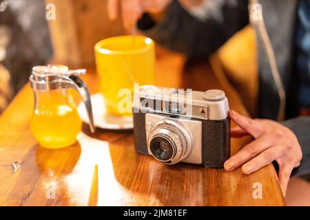 Una mano di un turista con una macchina fotografica che ha un tè in una caffetteria Foto Stock