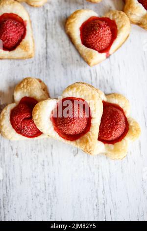 Biscotti di pasta sfoglia a forma di cuore pieni di fragole. Dessert party Foto Stock