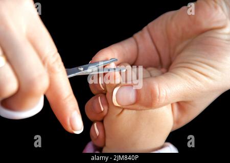 Madre taglia le unghie con le forbici Foto Stock